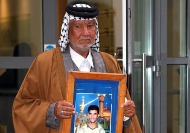 The father of Hamid Al-Sweady carries a photo of his son after leaving the inquiry into his death. Picture: PA