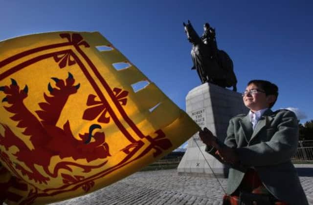 Benedict Bruce waves a flag as a restored statue of Robert the Bruce is unveiled in Bannockburn. Picture: PA