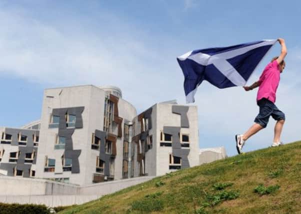 A woman runs with a Saltire outside the Scottish Parliament. Picture: TSPL