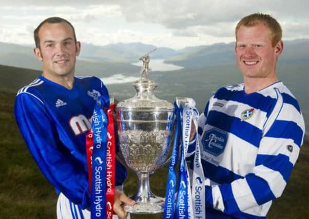 Newtonmore captain Jamie Robinson, right, holds the Camanachd Cup with Robbie MacLeod of Kyles Athletic. Picture: Jeff Holmes