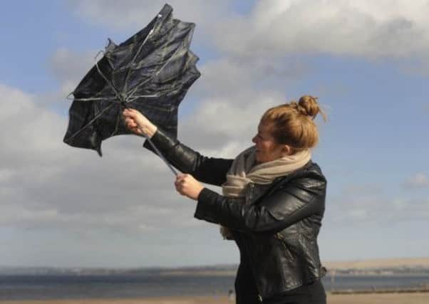 A woman struggles with her umbrella on Portobello Beach due to the high winds. Picture: Greg Macvean