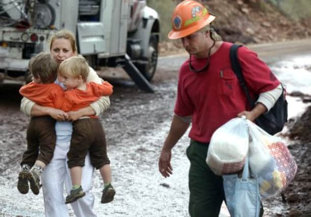 A woman and her two sons are evacuated by fire crews from their Boulder home. Picture: AP