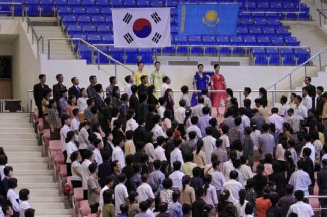 South Korean and Kazakhstan flags are hoisted over North Korean spectators at the Weightlifting Championships. Picture: AP