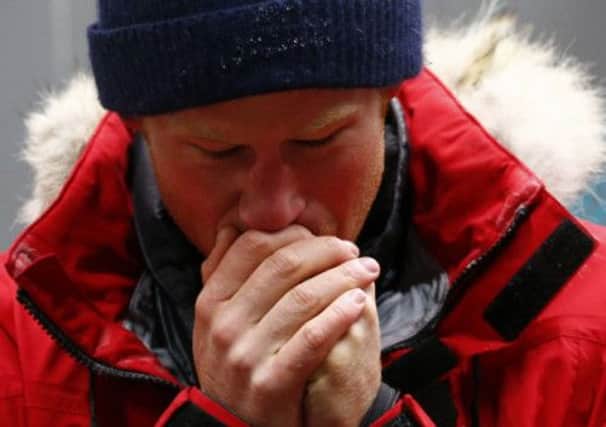 Prince Harry warms his hands. Picture: Reuters