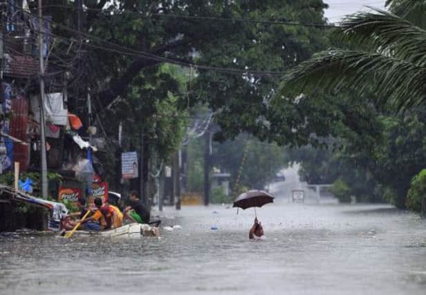 Here in Manila an optimistic pedestrian raises his umbrella, while a trishaw driver finds the going hard on the flooded street. Picture: Getty