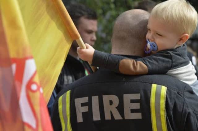 A firefighter's child joins strikers at Euston fire station  one of many to take part in yesterday's four-hour walkout.  Picture: Reuters