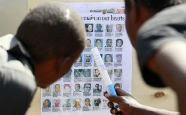 Two men in Nairobi study a newspaper page pasted to a wall that shows the victims of last week's fourday terrorist attack on the shopping centre.  Picture: Reuters