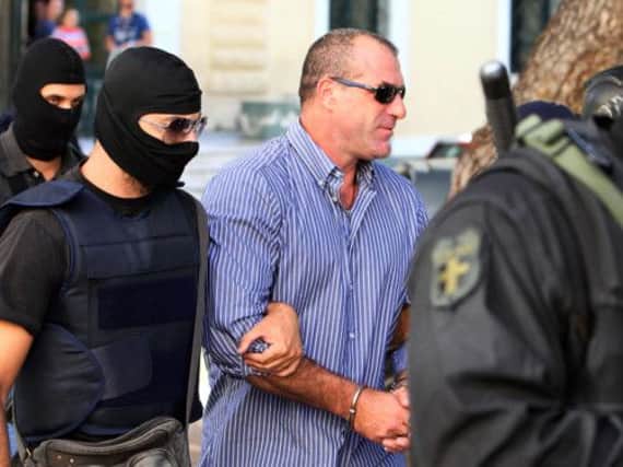 Nikos Michos arrives at court flanked by police. Picture: AP