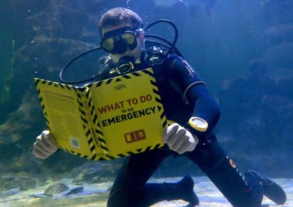Diver Lewis Jepson reads a book in the shark tank at Deep Sea World, North Queensferry. Picture: PA