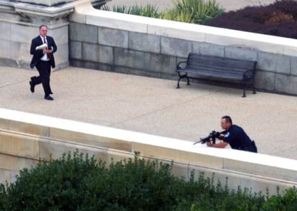 A man runs for cover as a police officer takes a shooting position on Capitol Hill. Picture: Getty