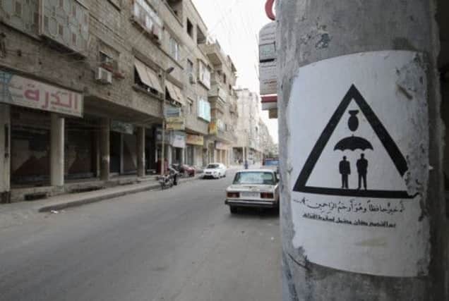This poster in a Damascus street warns neighbours not to gather lest shells fall on them. Picture: Reuters