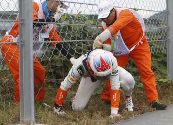 Race marshalls assist Paul di Resta as he squeezes under a fence. Picture: Reuters