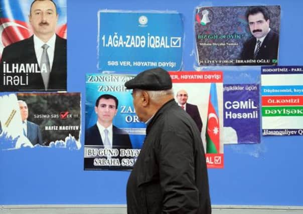One of Azerbaijans nine million voters walks past a hoarding covered in election posters. Picture: AFP/Getty