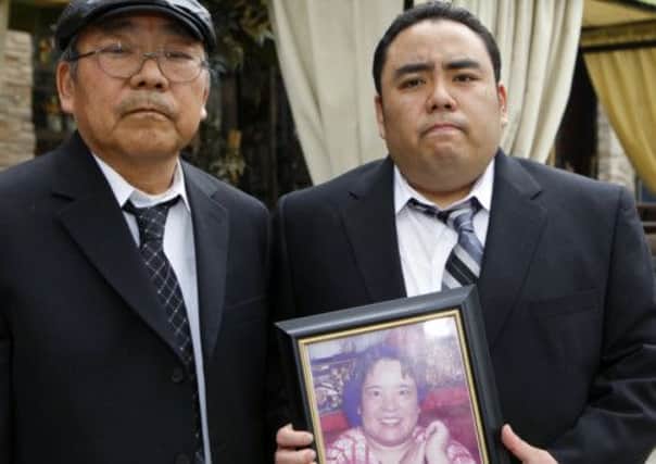 Peter Uno and his son Jeffrey, holding a picture of his mother. Picture: AP