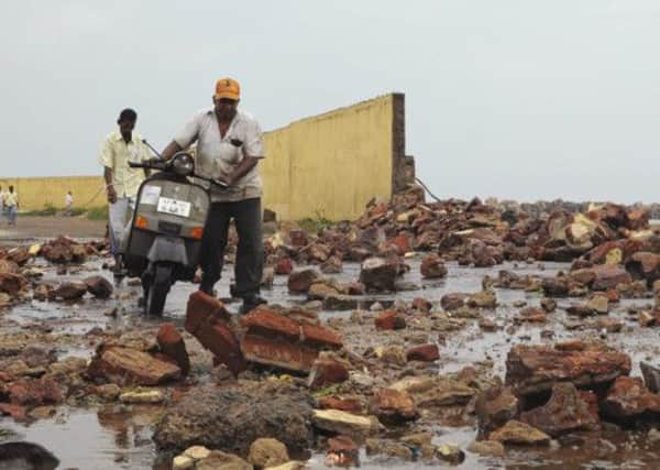 People walk among debris from a broken wall after it was damaged by a wave brought by Cyclone Phailin at a fishing harbour in Visakhapatnam district. Picture: Reuters