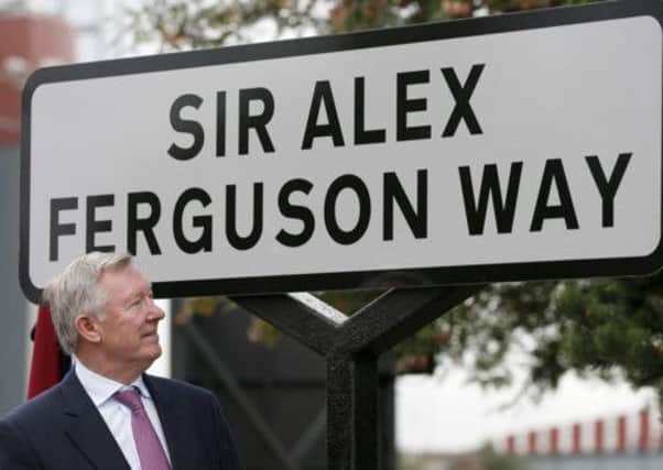 Former Manchester United manager Sir Alex Ferguson stands next to the newly-unveiled road sign bearing his name. Picture: Reuters