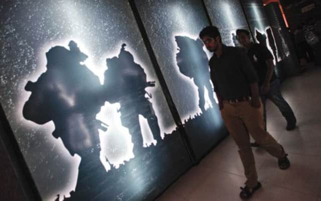 Cinema-goers in the Pakistani city of Karachi walk past posters promoting the film Waar, which portrays India as the enemy. Picture: Reuters
