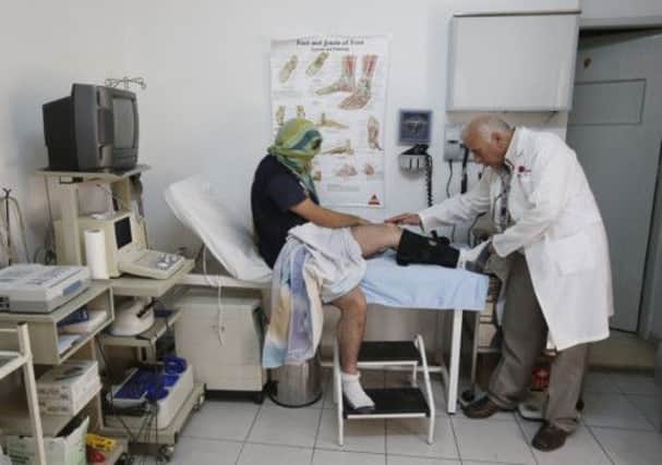 A Syrian refugee receives medical care from a doctor at a Caritas Jordan community centre in Amman.  Picture: PA