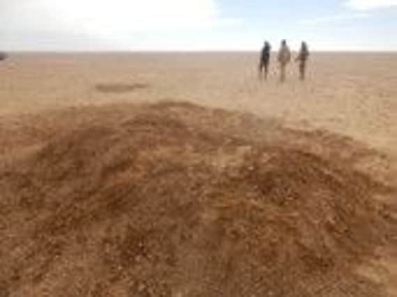 Soldiers walk away from the freshly dug grave in the Sahara Desert north of Arlit, Niger. Picture: AP