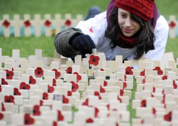 Volunteer Sophie Thurlow helps put up all the crosses in the Garden of Remembrance by the Scott Monument. Picture: Greg Macvean