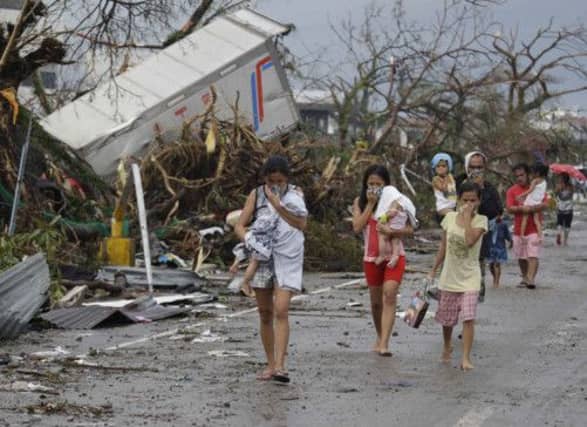 Residents cover their nose from the smell of dead bodies in Tacloban City. Picture: AP