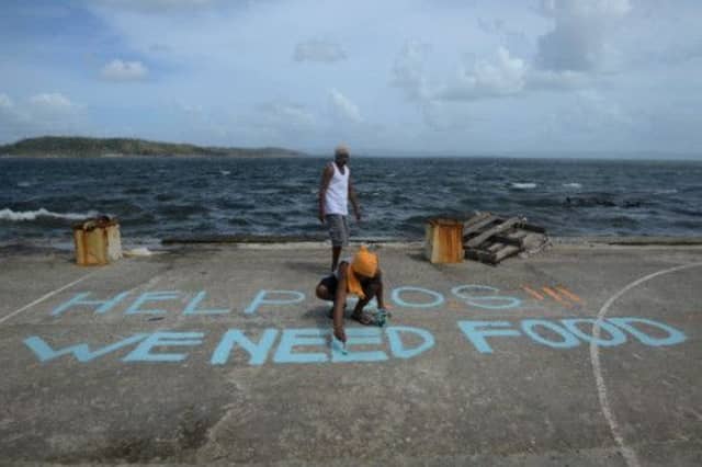 A man paints an SOS message on a basketball court. Picture: AFP/Getty