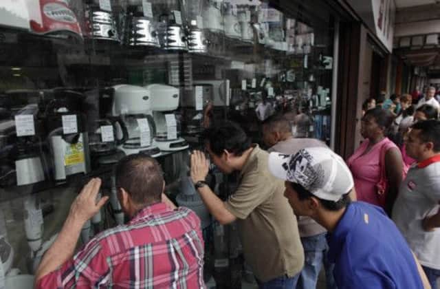 People peer into the storefront window of an appliance store in Caracas. Picture: Ariana Cubillos/AP