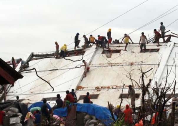 Residents climb on the damaged warehouse in Alangalang, Leyte. Picture: Getty
