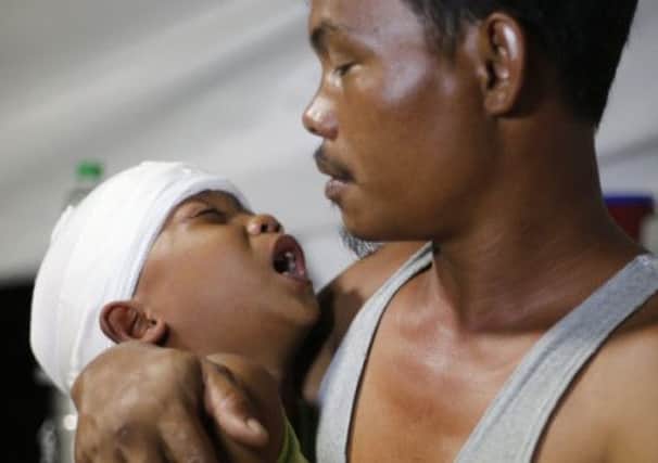 Seven-year-old Adrian cries in his fathers arms after head surgery in Palo, Leyte. Picture: Reuters