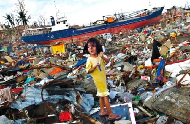 A girl stands amidst the debris at a destroyed community where ships washed ashore. Picture: Reuters