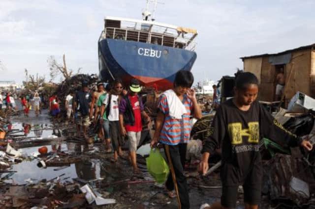 Survivors walk past stranded boats in Tacloban's port. Picture: Reuters