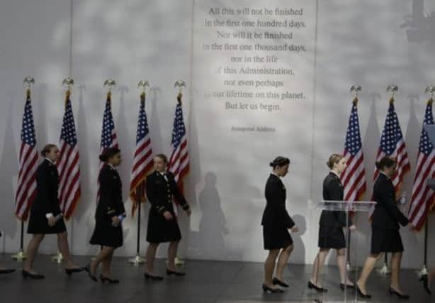 Members of the U.S. Naval Academy Women's Glee Club walk under a passage from President John F. Kennedy's inaugural address. Picture: AP