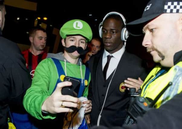 Mario Balotelli (right) poses with a fan dressed as Luigi as the squad arrive in Glasgow ahead of their clash with Celtic. Picture: SNS