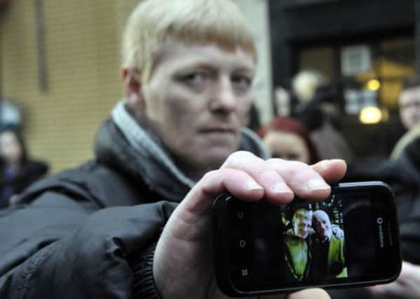 John McGarrigle, 38, holds his mobile phone displaying a picture of himself with his father. Picture: Getty
