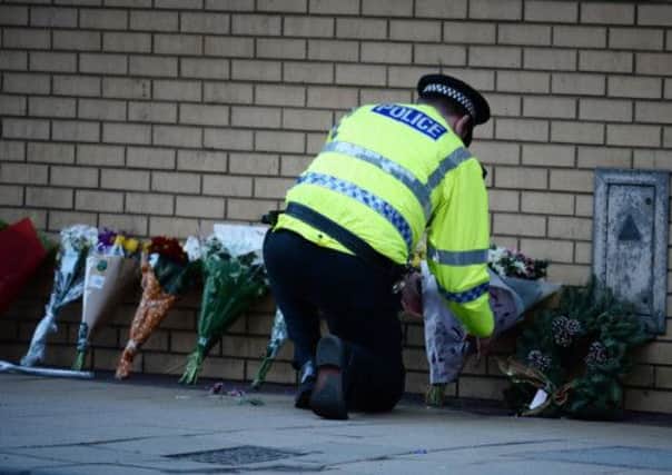 A police officer lays flowers near the scene where a police helicopter crashed into a pub. Picture: Getty