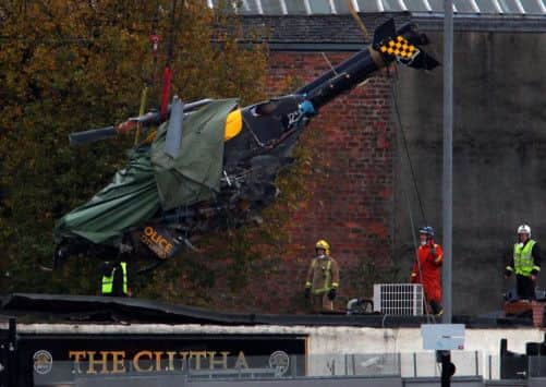 Rescue and emergency service workers use a crane to remove the wreckage of the crashed police helicopter. Picture: Hemedia