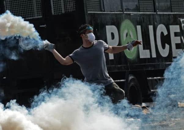 A protester throws a tear gas canister at police outside Government House in Bangkok. Picture: Getty