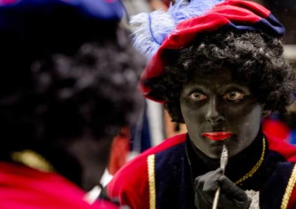 A woman paints herself in the guise of Zwarte Piet for the Sinterklaas festival, below. Picture: Getty