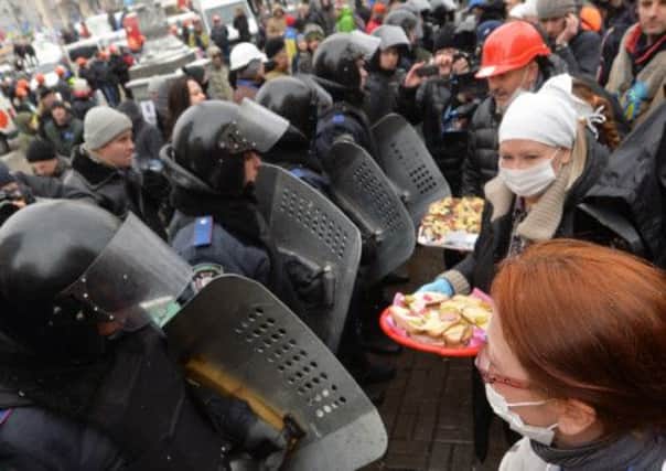 Protesters offer sandwiches to riot policemen standing guard in Independence Square. Picture: AFP/Getty