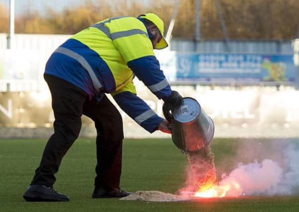 A steward tries to put out a flare on the plastic pitch at Falkirk. Picture: SNS