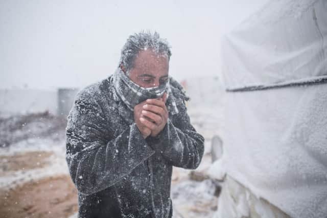 A Syrian refugee blows on his hands to keep warm at Terbol camp. Picture: Andrew McConnell/UNHCR