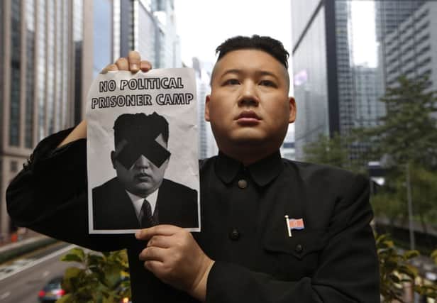 A Kim Jong-un impersonator poses with a defaced poster of the North Korean leader. Picture: AP