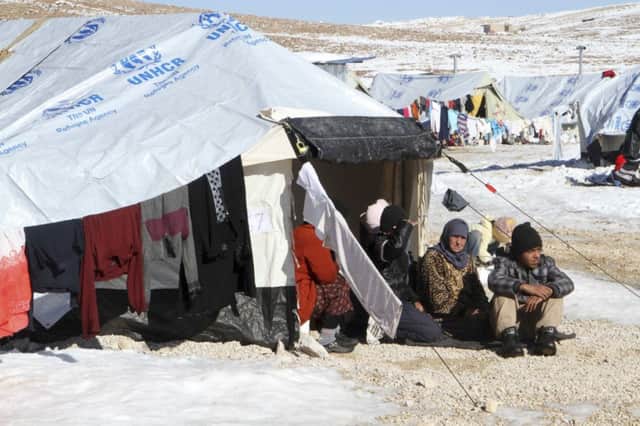 Syrian refugees sit by their tent in a refugee camp in the Lebanese border town of Arsal. Picture: Reuters
