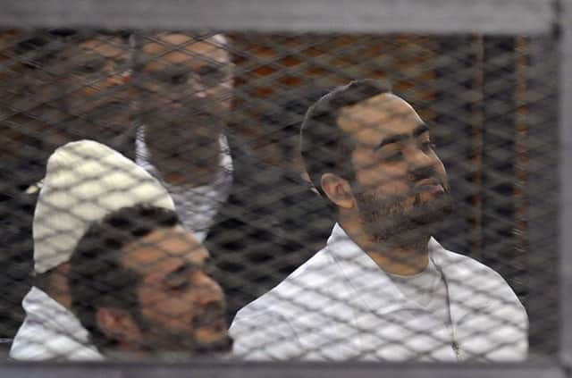 Ahmed Maher, Ahmed Douma and Mohamed Adel look on from behind bars in Cairo. Picture: Reuters