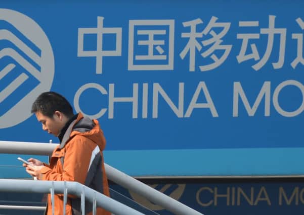 A man uses his mobile phone as he walks past a China Mobile sign on a street in Shanghai. Picture: Getty