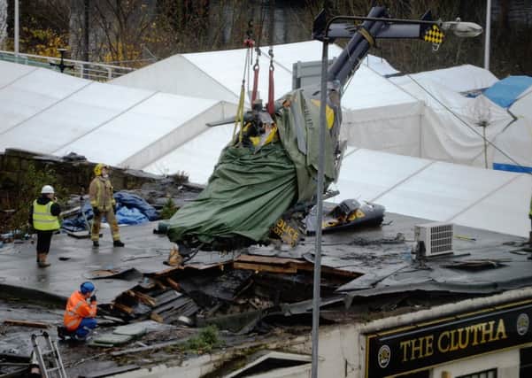 Rescuers lift the police helicopter wreckage from the roof of the The Clutha earlier this month. Picture: Getty