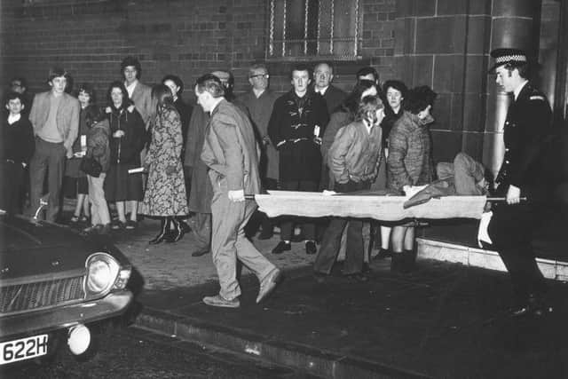 Neilly Mochan, the Celtic Coach, helps carry an injured fan from Ibrox after the disaster. Picture: TSPL