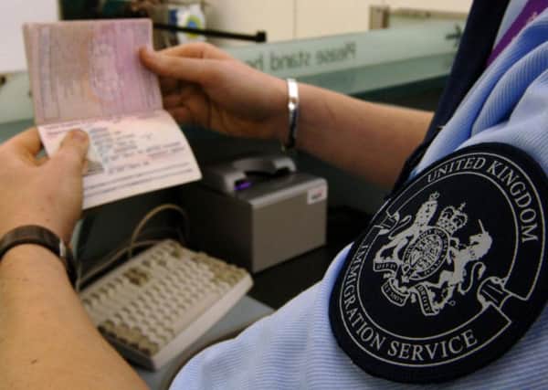 An immigration officer checks a passport. Picture: PA