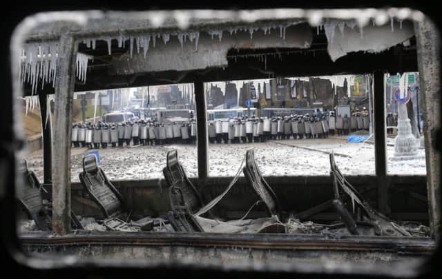 Seen through the windows of a burnedout bus, police form a cordon in the centre of Kiev yesterday. Picture: AP