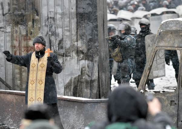An Orthodox priest tries to stop clashes between protesters and the police. Picture: Getty